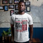 tshirt-mockup-of-a-man-standing-against-a-wall-with-framed-pictures-a17168